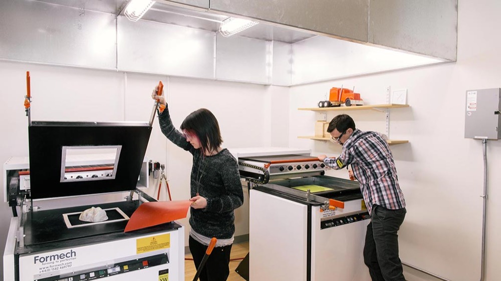 Two makers learning to operate a vacuum former